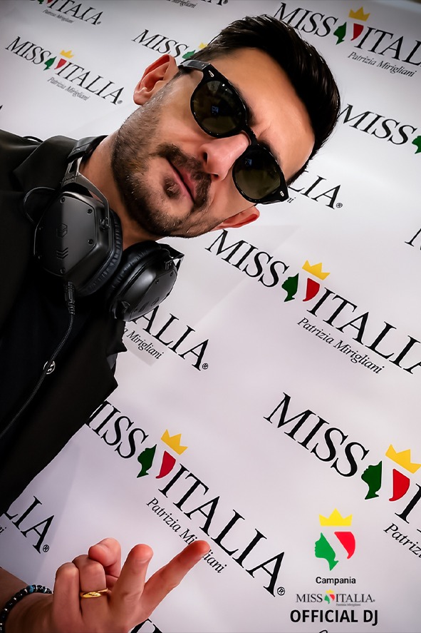 Jespo davanti al fondale Miss Italia, con la cuffia al collo